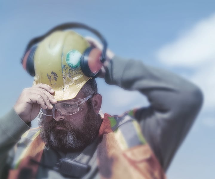 Blue collar worker putting on hard hat